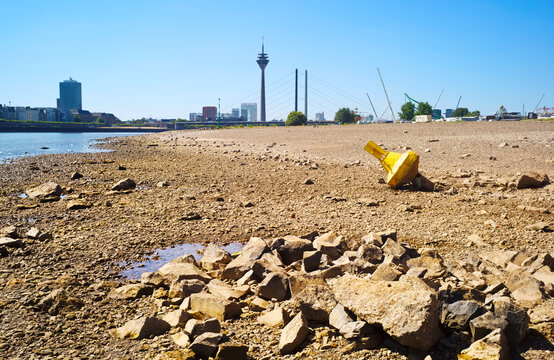 Low stream gauge of rhine river in D&uuml;sseldorf,Germany.Water shortage, drought, climate change,global warming concept, dry river bed with skyline of the town of d&uuml;sseldorf, germany in the background 