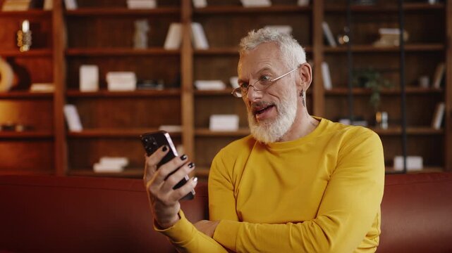 Fashionable mature man talking with a friend via smartphone video call