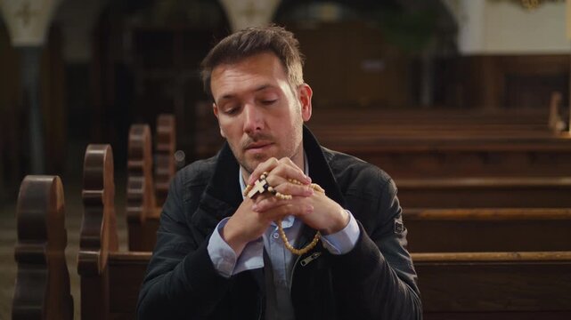 Private moment of prayer, a man sitting on a wooden pew in a peaceful, empty Christian church, praying with rosary beads.