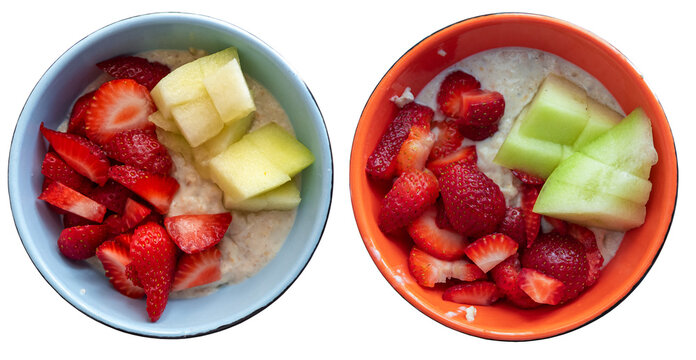 Against a transparent background are two bowls of oatmeal. One bowl contains strawberries and melon, while the other contains strawberries and pieces of a different kind of melon. The photo shows a si