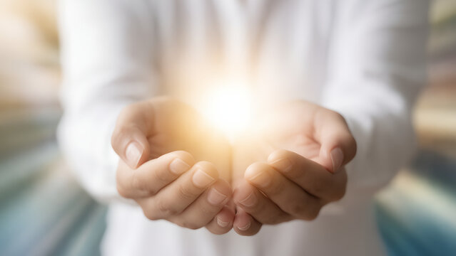 Person holding glowing light in cupped hands representing hope and inspiration.
