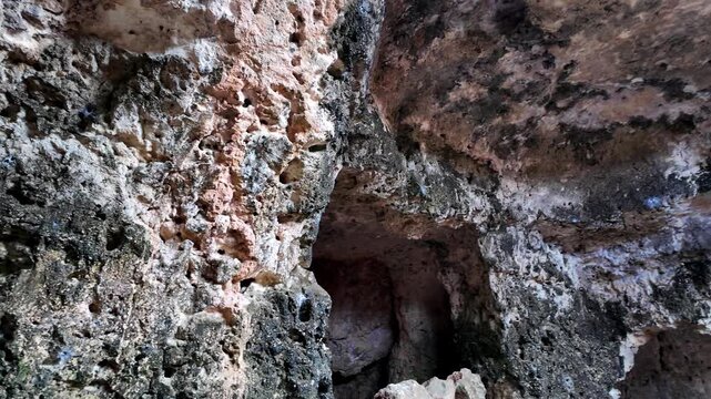 Xemxija, Malta 29.07.2026 - Heritage trail, Roman Baths, shelf like cut in the stone Dark cave walls show rough, textured surfaces. Greenish moss grows on damp, uneven stone. Light filters through nar