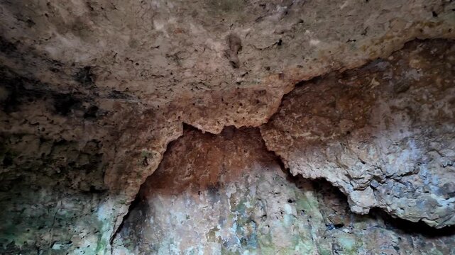 Xemxija, Malta 29.07.2026 - Heritage trail, Roman Baths, shelf like cut in the stone Dark cave walls show rough, textured surfaces. Greenish moss grows on damp, uneven stone. Light filters through nar