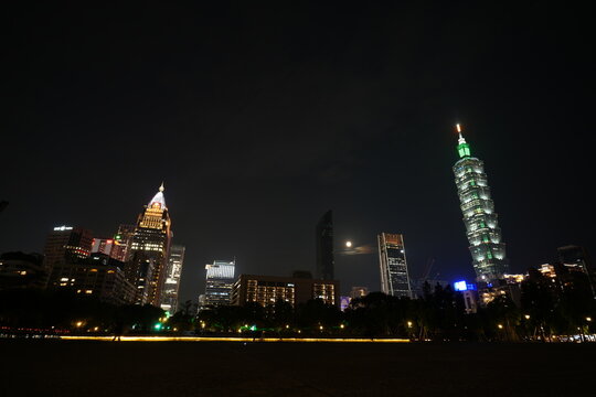 Taipei skyline and Taipei 101 illuminated at night with moon.