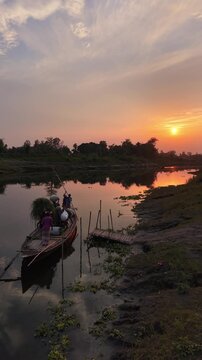 Serene river sunset with traditional wooden boat carrying harvest and people tranquil water
