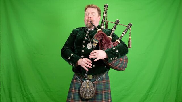 Man in kilt plays bagpipes on green screen