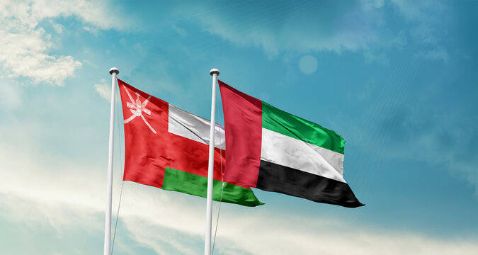 Oman and UAE friendship flags are waving in the sky. Double country Flag waving with mast. Oman UAE national flag for agreement.