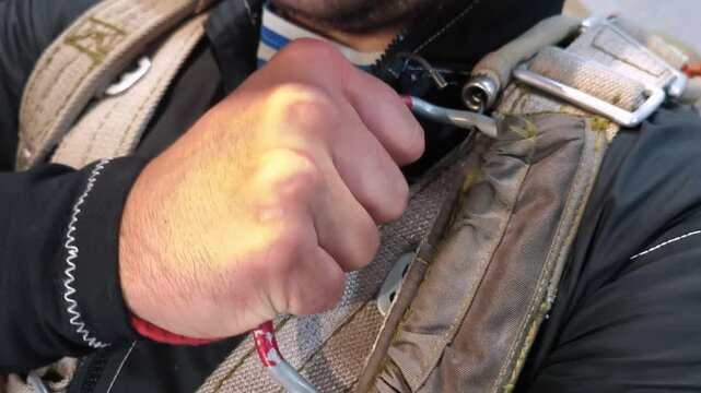 The paratrooper tightly squeezes the parachute opening ring before jumping. A close-up of the parachute system element and the preparation for the landing.
