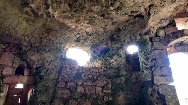 Xemxija, Malta 29.07.2026 - Heritage trail, Roman Baths, shelf like cut in the stone Dark cave walls show rough, textured surfaces. Greenish moss grows on damp, uneven stone. Light filters through nar
