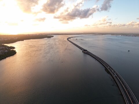 Aerial view of the Mandara Toll Road stretching across the water at sunset in Kabupaten Badung, Bali, Indonesia.