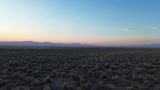 Evening over a summer desert in Nevada showcasing the outline of distant hills and low sage brush.