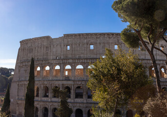 Obraz premium Famous Coliseum in Rome. Colosseum, or Coliseum. Part of the wall of an antique stone structure with arches. Italy, Europe. Famous touristic place in the world, Europe. Beautiful blue sky background.