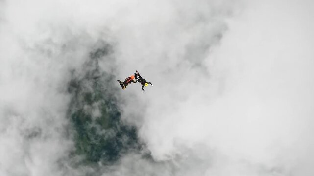 Two athletes perform elements of group acrobatics in free fall among the clouds. Extreme sports, altitude and the feeling of flying.
