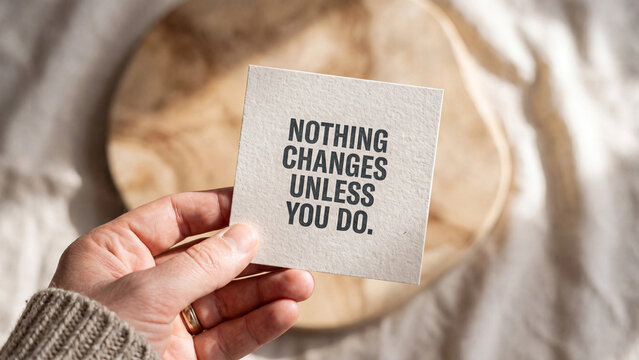 Hand holding a small square card with the inspirational quote nothing changes unless you do printed on textured paper