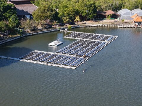 Aerial view of the PLN Indonesia Power floating solar farm on the Muara Nusa Dua reservoir, featuring rows of solar panels in Kecamatan Denpasar Selatan, Bali, Indonesia.