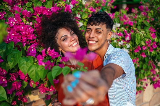 Young couple shares a joyful moment outdoors while appreciating beautiful blooming flowers together