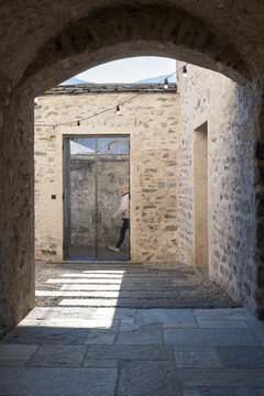 A detail of an inner courtyard in an old, renovated house with stone walls. In the background is an iron gate.