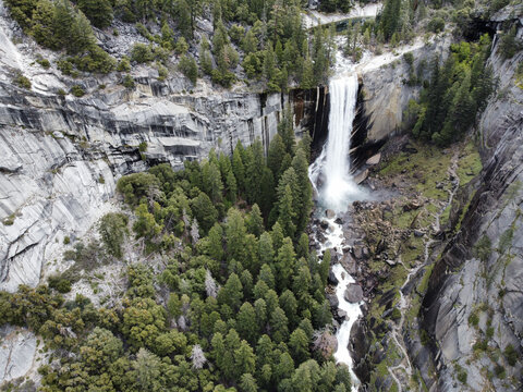 Aerial view of Vernal Fall cascading over granite cliffs surrounded by dense pine forests in Yosemite Valley, California, United States.