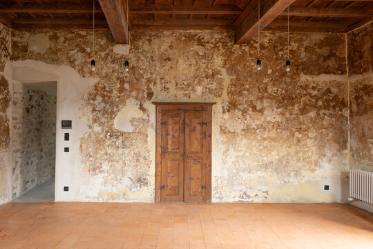 A beautiful old, faded, and weathered wall in a fully renovated room with light bulbs hanging from the ceiling. Great for a backdrop. Front view.