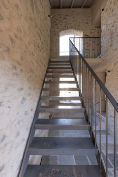 A front view of an iron or steel staircase leading up to the next floor. The handrail is also made of iron.