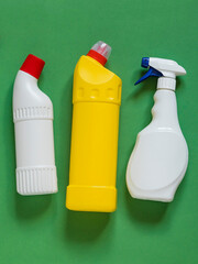 Collection of household cleaning bottles arranged on a green backdrop, representing domestic cleaning, disinfecting, surface care, and everyday home maintenance. © Tanya