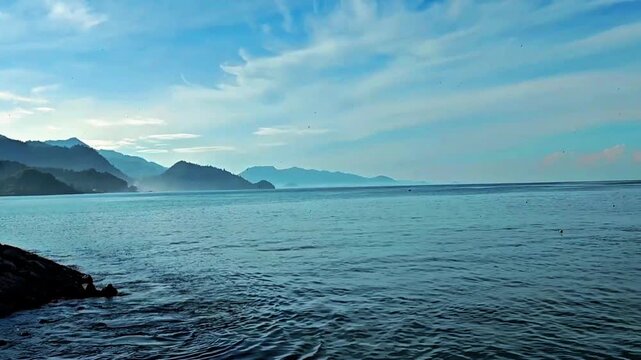 Calm Blue Ocean with Coastal Mountains Under Dramatic Cloudy Sky
