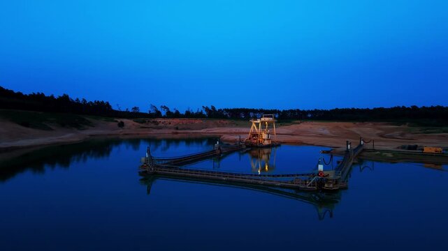 Gravel dredger on lake at dusk, aerial orbit