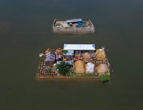 Aerial view of Kishoreganj Haor featuring a small island with traditional houses, haystacks, and a boat in the wetland landscape of Kishorganj, Dhaka Division, Bangladesh.