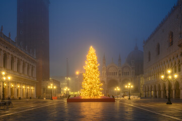 Naklejka premium Illuminated Christmas Tree in Front of St. Mark's Basilica in Fog and Soft Light at Night