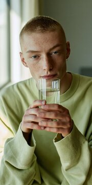 Portrait of young person drinking water from a glass for wellness lifestyle background and calm interior banner design