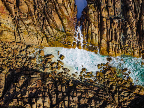 Aerial view of Canal Rocks Bridge with rugged granite rock formations and turquoise ocean waves crashing against the coastline in Yallingup, Western Australia, Australia.