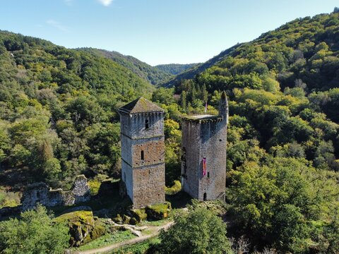 Aerial view of the medieval stone towers of Tours de Merle surrounded by a dense green forest in Argentat-sur-Dordogne, Nouvelle-Aquitaine, France.