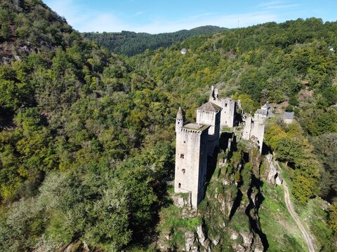 Aerial view of the medieval ruins of Tours de Merle perched on a rocky outcrop surrounded by dense forest in Argentat-sur-Dordogne, Nouvelle-Aquitaine, France.