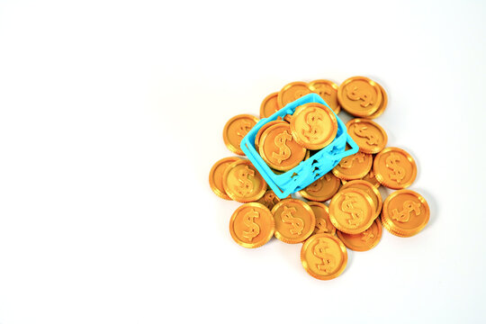 Miniature blue shopping basket overflowing with gold dollar coins on a clean white background. Concept for retail sales, consumer spending, e-commerce, and financial investment growth.