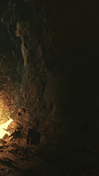 Light enters a cave and illuminates the rocky walls. Shadows form as the light creates a contrast against the dark corners. Sounds of dripping water echo softly in the cave.