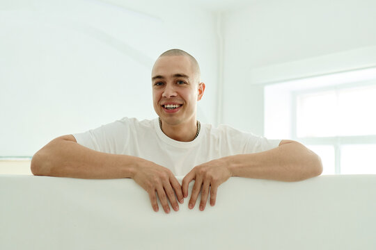 Portrait of young adult Caucasian male artist smiling into camera while leaning on blank panel, presenting creative identity and copy space for branding or promotion