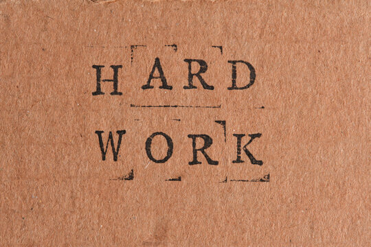 Phrase HARD WORK stamped in black ink on brown craft paper, centered for business concept designs.