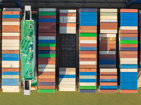 Aerial view of colorful shipping containers stacked on a cargo ship deck in the United Kingdom.