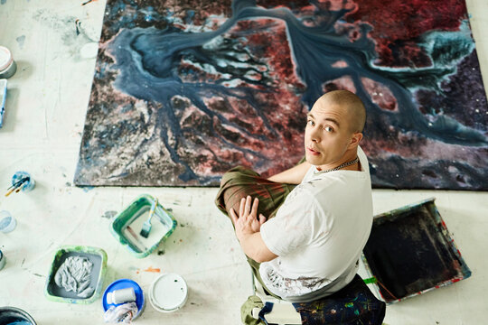 Portrait of young adult Caucasian male artist creating abstract painting in studio, expressing contemporary creativity. Useful for art marketing, creative business branding, overhead shot