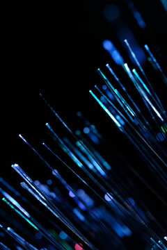 Luminous blue optical fibers casting bright glow with blurry bokeh circles in vertical format.