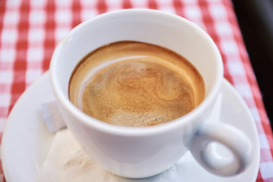 Close-up view of freshly brewed hot coffee in a white cup on a saucer