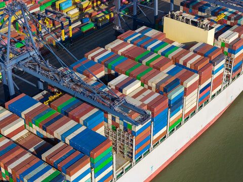 Aerial view of a container ship being loaded with colorful shipping containers by a large crane, United Kingdom.