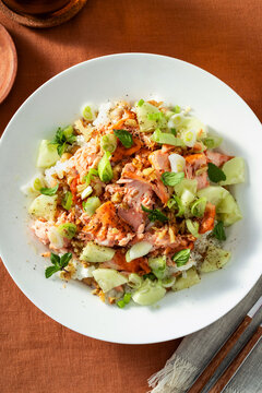Close up of baked salmon salad with cucumbers, chickpeas, walnuts, feta and rice on a summer style dining table