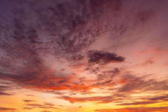 Vibrant Purple and Orange Sunset Sky with Textured Clouds,A breathtaking view of a dramatic sunset sky filled with vibrant purple, blue, and fiery orange clouds, creating a stunning colorful backgroun