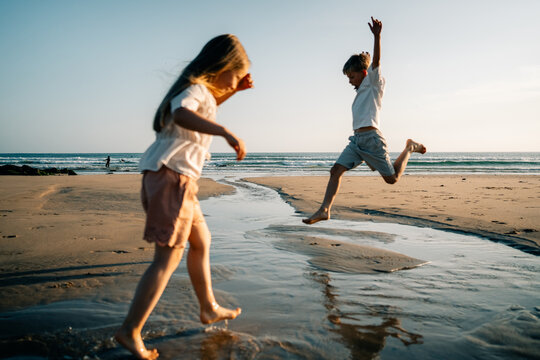 Children Play at the Beach During Sunset While Splashing Water