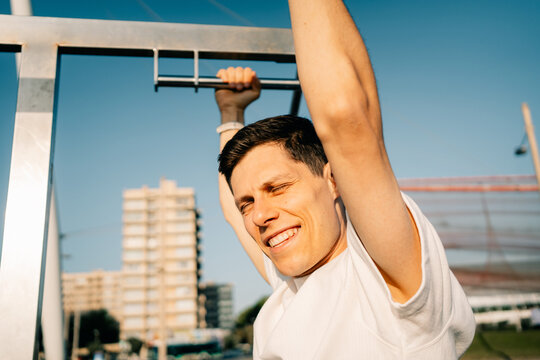 Man Exercises on Fitness Bar in Outdoor Park During Sunny Day