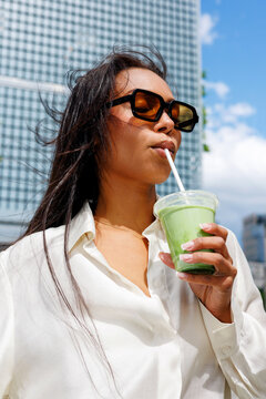 Woman drinking matcha tea outdoors in city