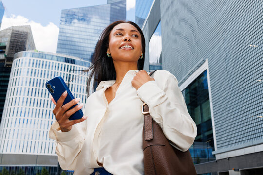 Woman holding smartphone walking in downtown city