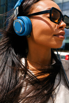 Woman wearing blue headphones and sunglasses outdoors