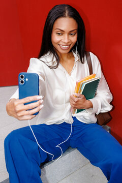 Woman taking selfie with smartphone and earphones